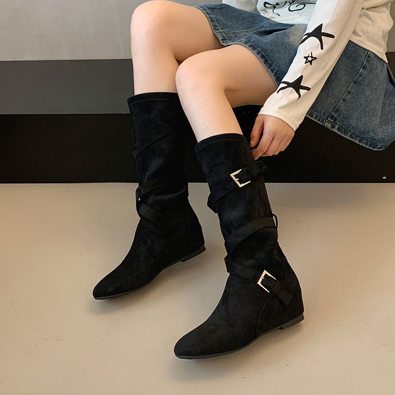 Black slouchy long boots with fold-over shaft and square buckle straps, low wedge heel.
