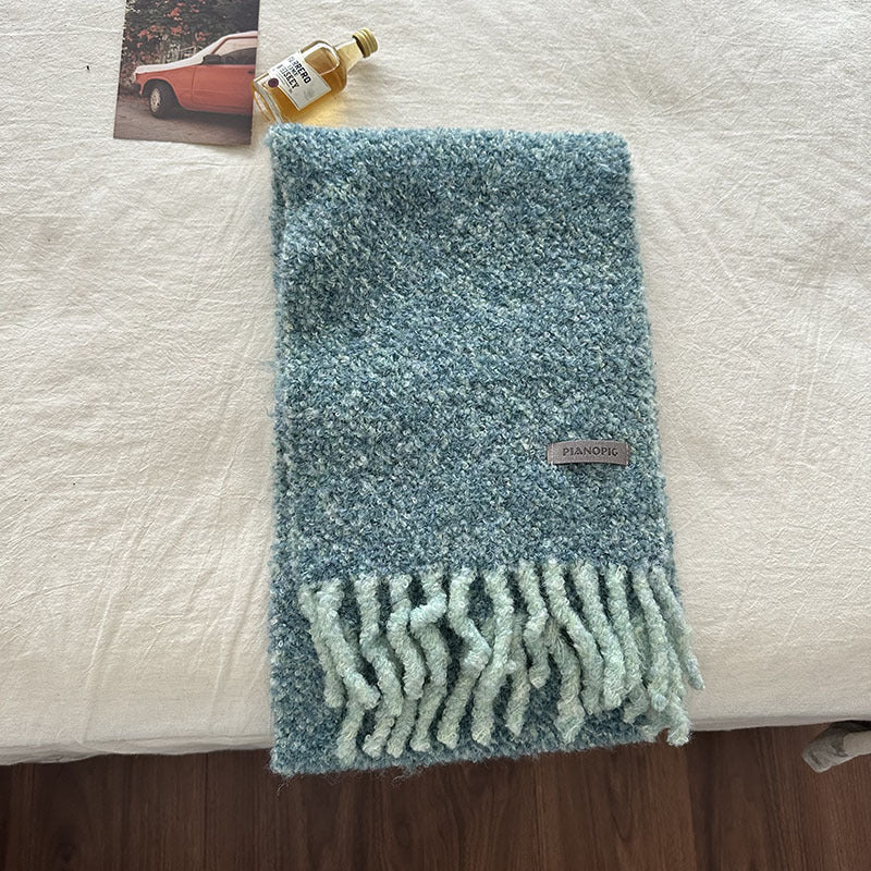 Teal-blue chunky loop-knit scarf with fringed bottom edge and rectangular brand tag