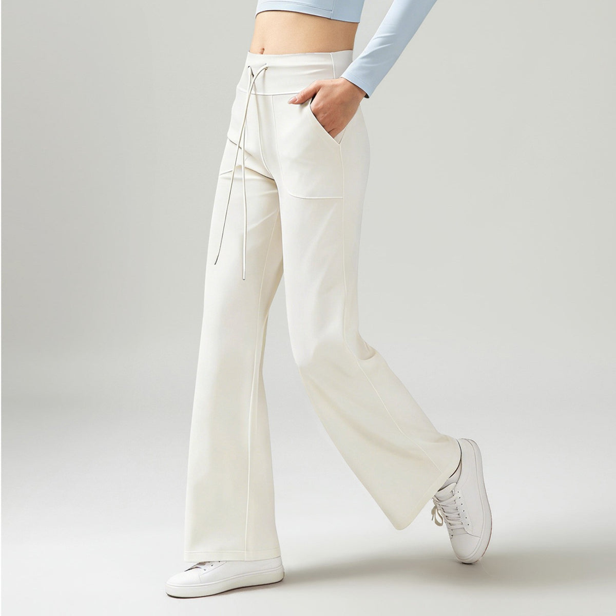 Women’s high-waisted wide-leg pants with drape, white, side drawstring ties and pockets.