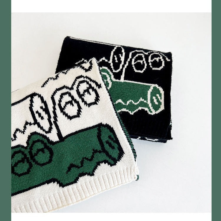 Black and white knitted scarf with green motif panels and ribbed hem