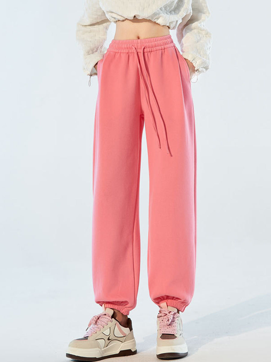 Pink high-waist sweatpants with elastic waist, drawstring, and relaxed tapered legs.