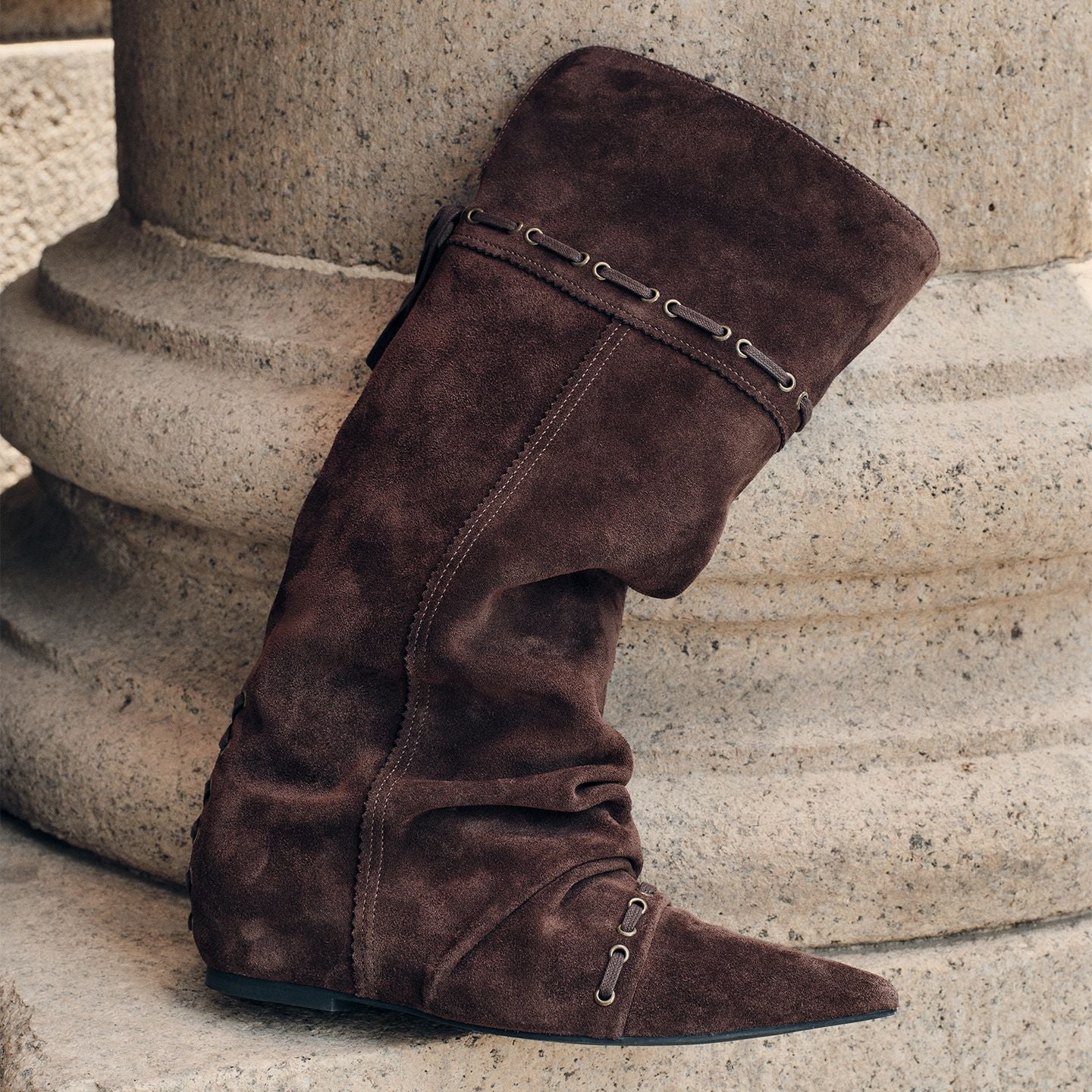 Brown knee-high slouch boots, pointed toe, side lace-up strap and buckle detail