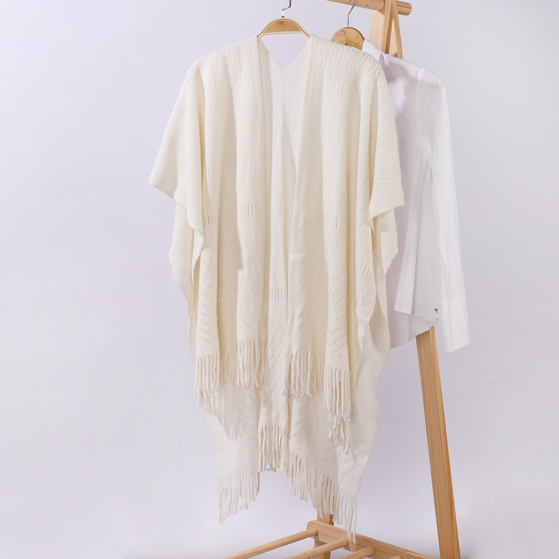 Off-white knitted shawl cape with openwork panels and long tassel fringe