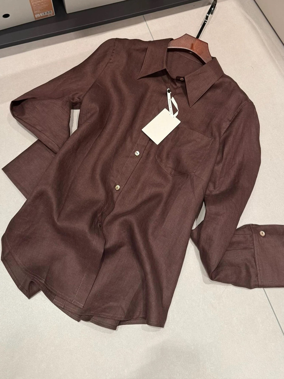 Dark brown linen shirt with point collar, long sleeves, and buttoned cuffs.