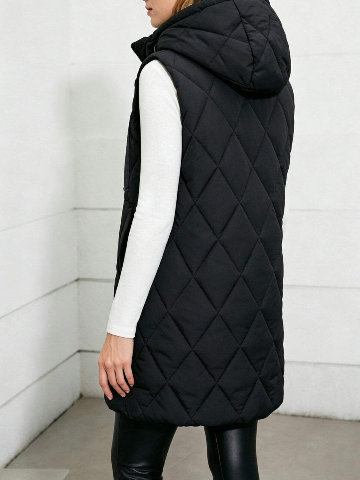 Black hooded quilted sleeveless vest, mid-length, side view with drawstring hood