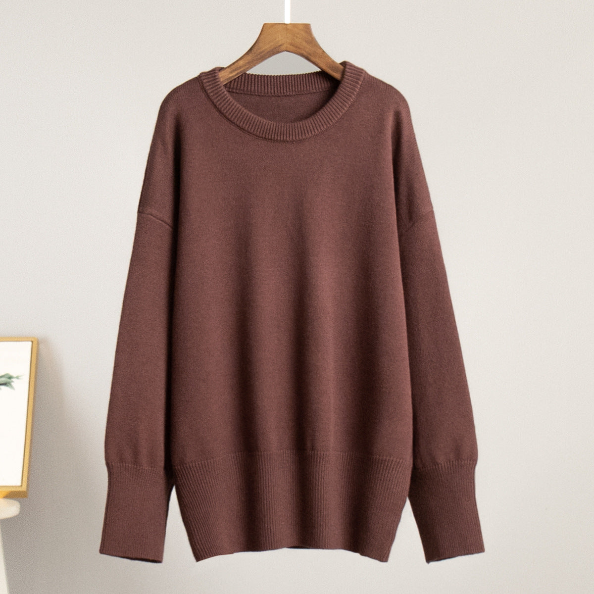Brown round-neck knit sweater on a hanger with ribbed collar and hem
