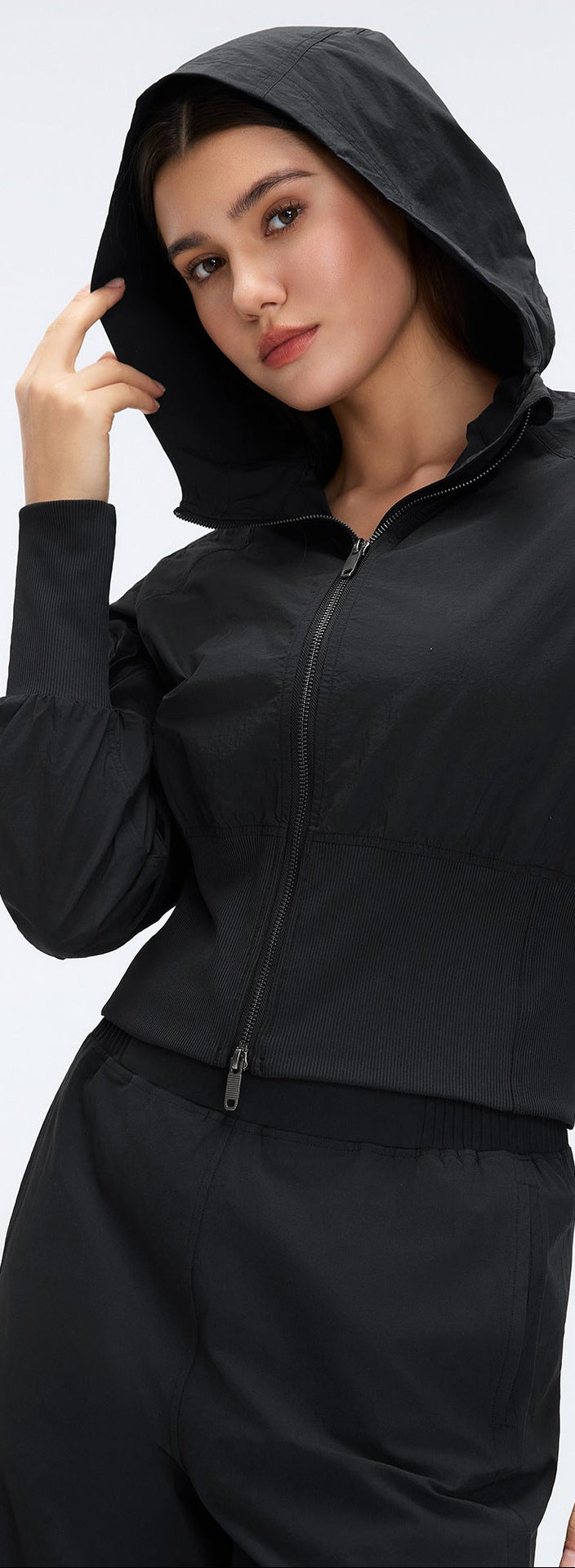 Black cropped hooded zip-up windbreaker with cinched ribbed waist and zip front