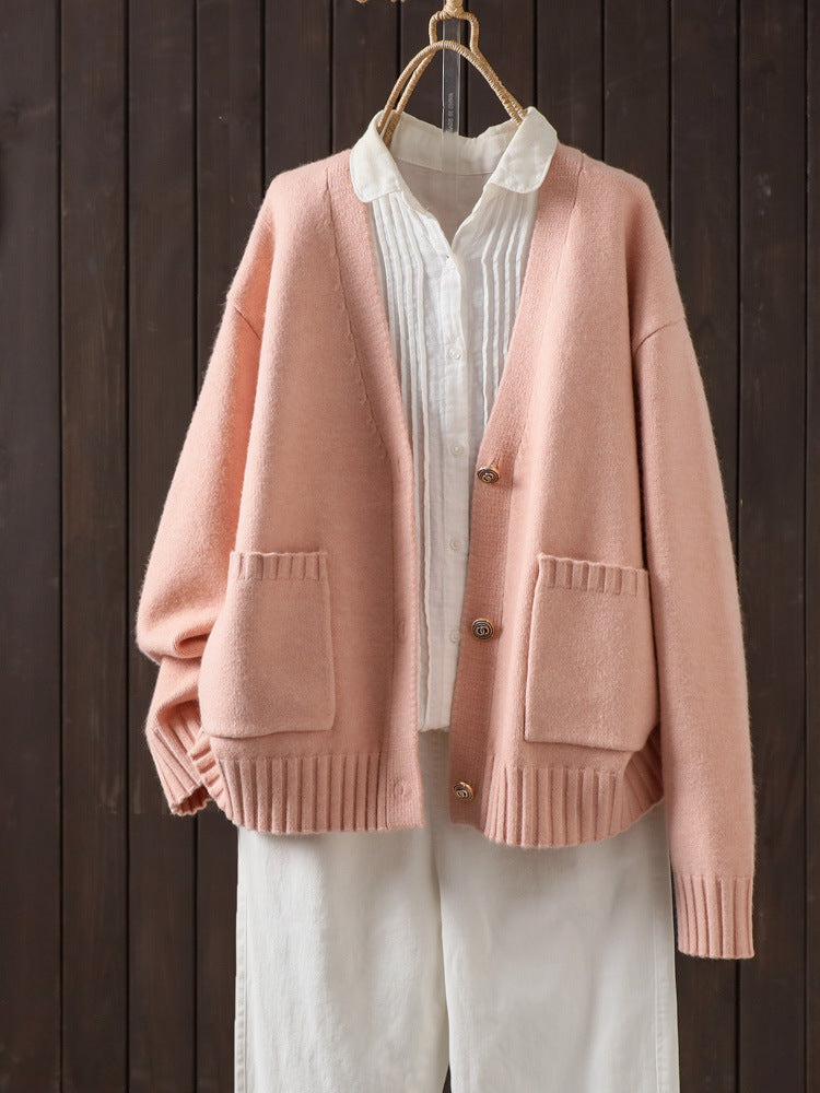 Pink wool cardigan on hanger with V-neck button front and patch pockets