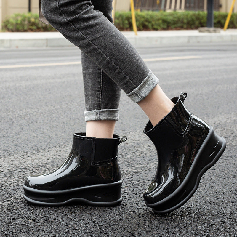 Black glossy mid-calf rain boots with cushioned platform sole and pull-tab strap