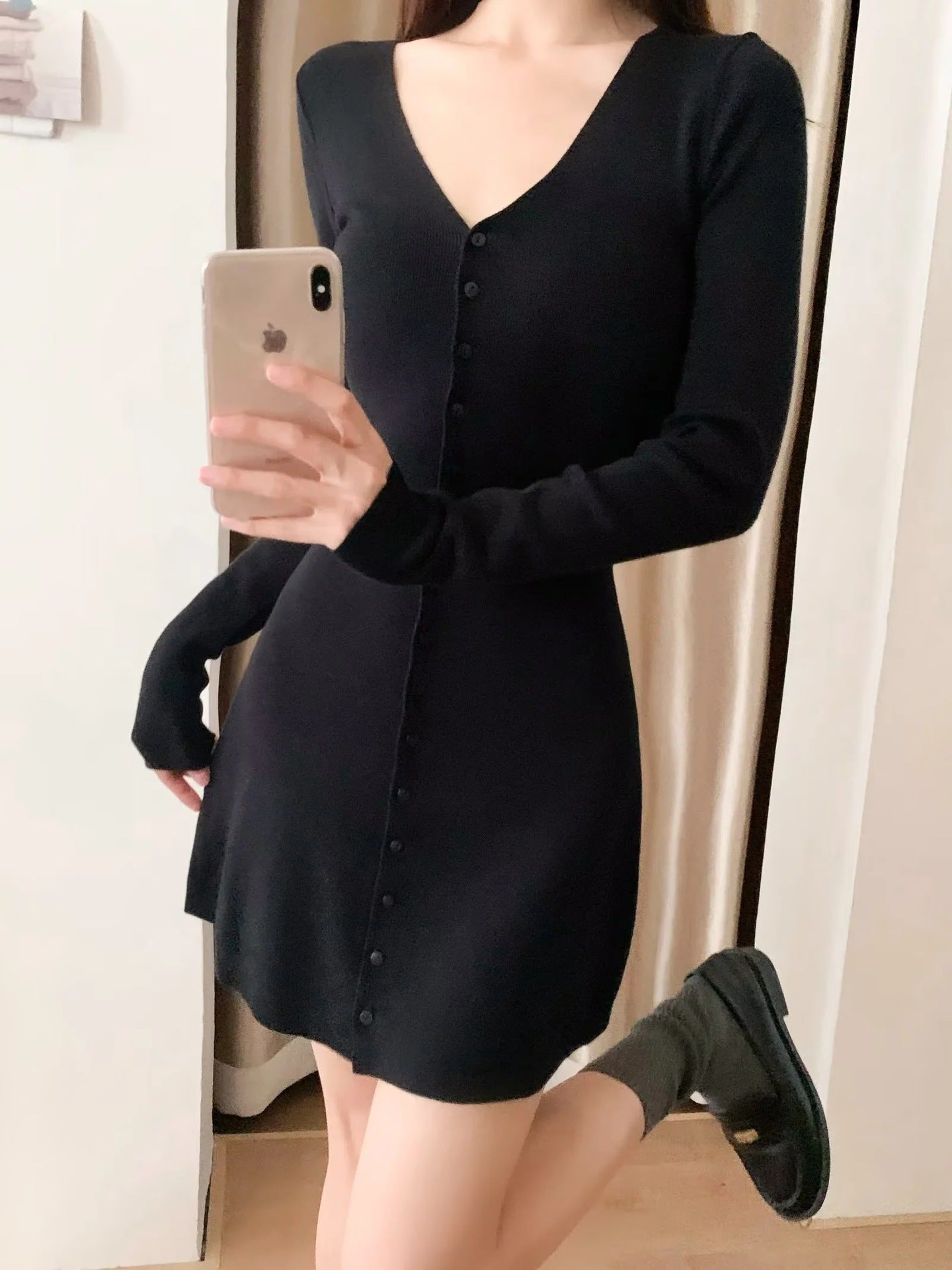 Black knit mini dress with V-neck and button front, long sleeves, A-line mini length.