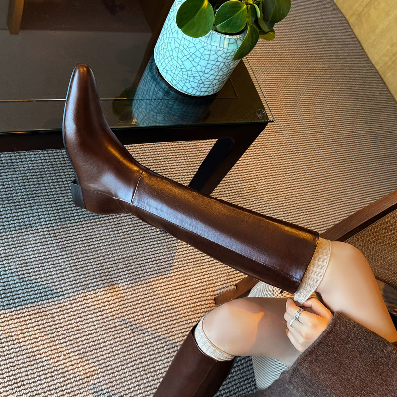 Brown knee-high leather boots with pointed toe and hidden heel, side close-up
