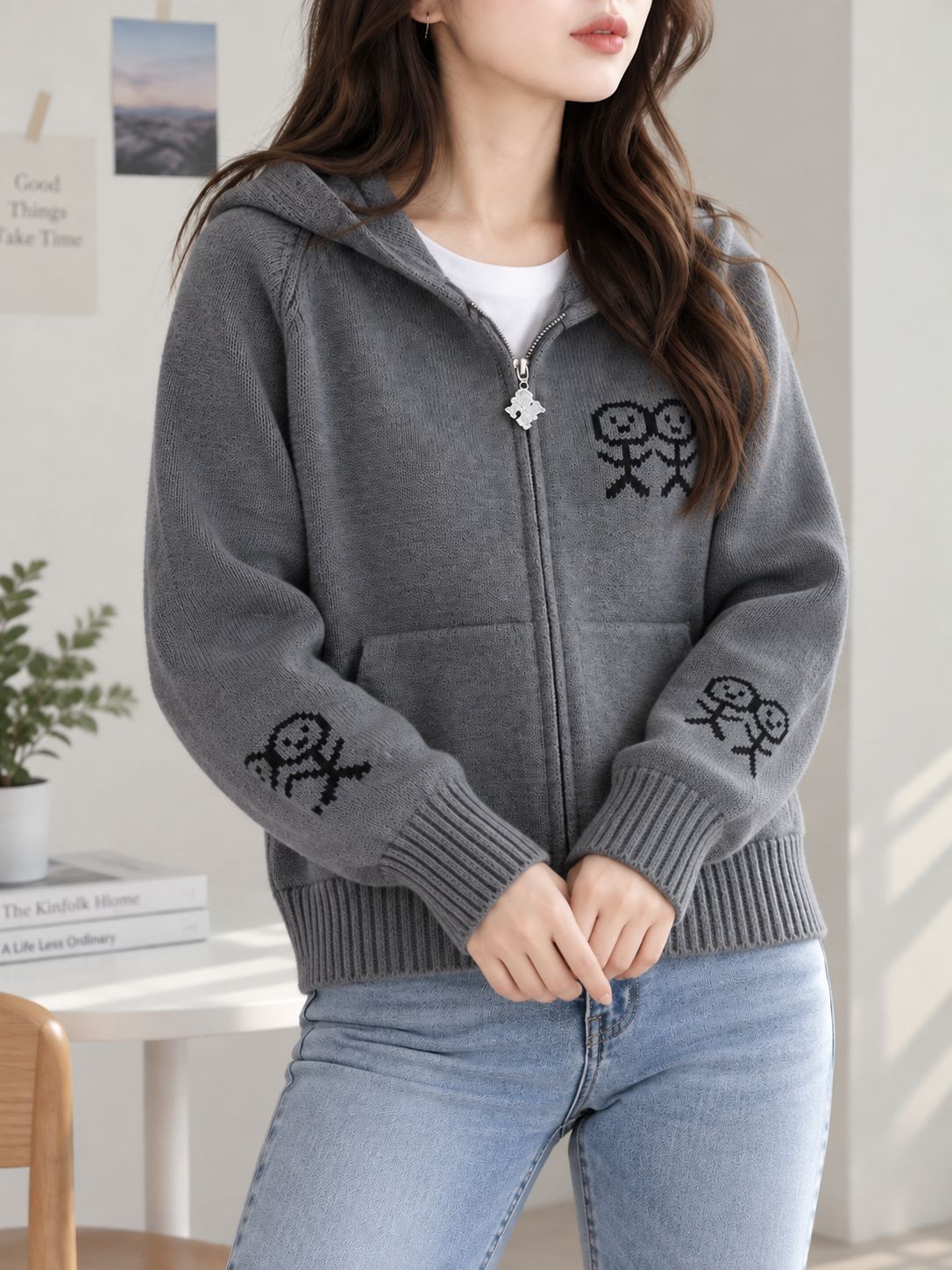 Gray zip-up hooded knit cardigan with graphic patches and front pockets.