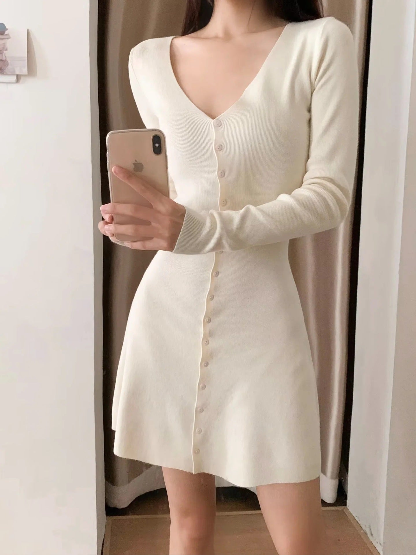 White knit mini dress with V-neck and button front, long sleeves, A-line silhouette.