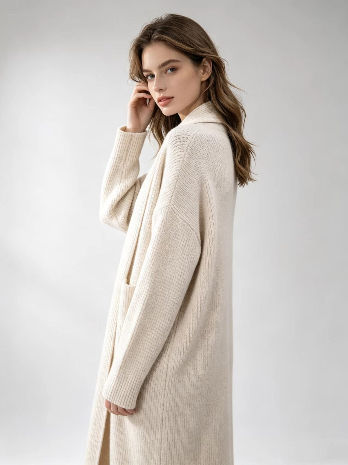 Off-white knitted cardigan sweater with open front, long sleeves, and patch pockets