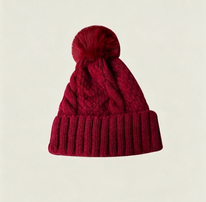 Wine red cable-knit winter hat with ribbed cuff and fluffy pom-pom