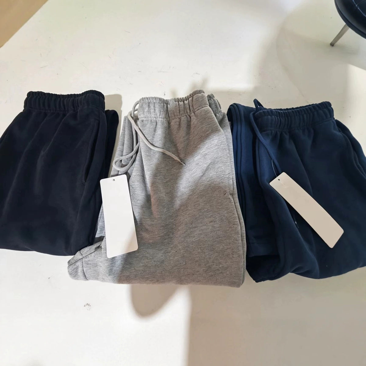 Three fleece jogger sweatpants in navy, gray, and black with drawstring waists