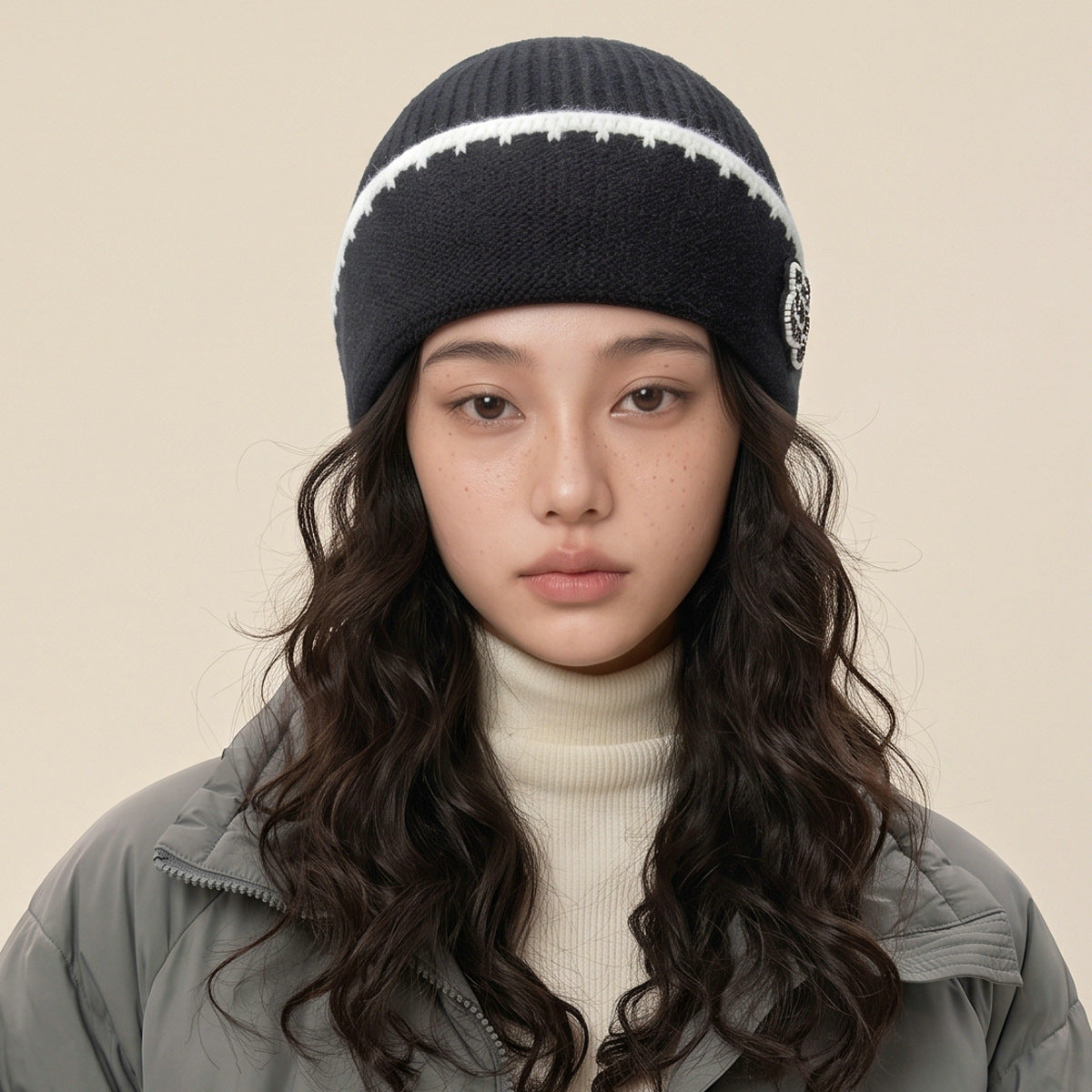 Knitted beanie hat in black with white trim and a side embellishment