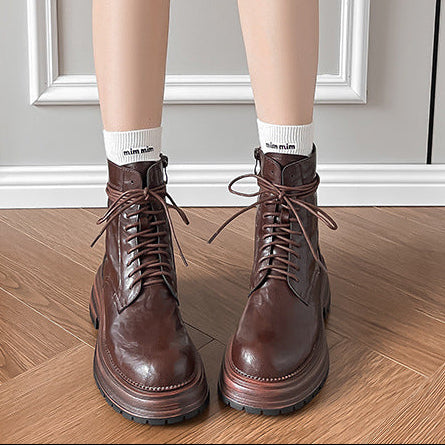 Brown lace-up ankle combat boots on feet, round toe and treaded sole
