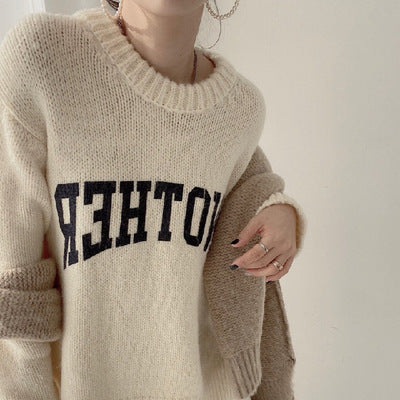 Beige chunky knit crewneck sweater with black slogan graphic across chest