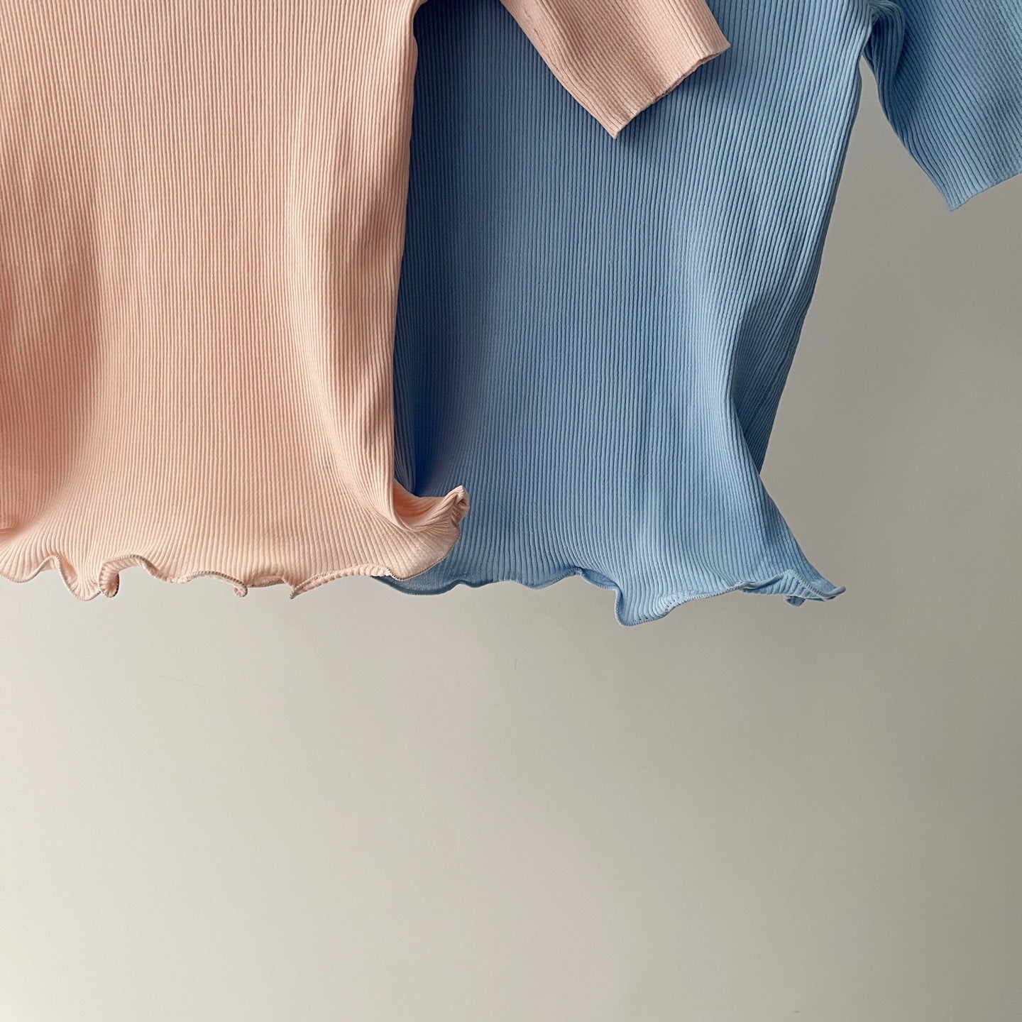 Women's knit polo hem details, scalloped lettuce edge in blush pink and light blue.