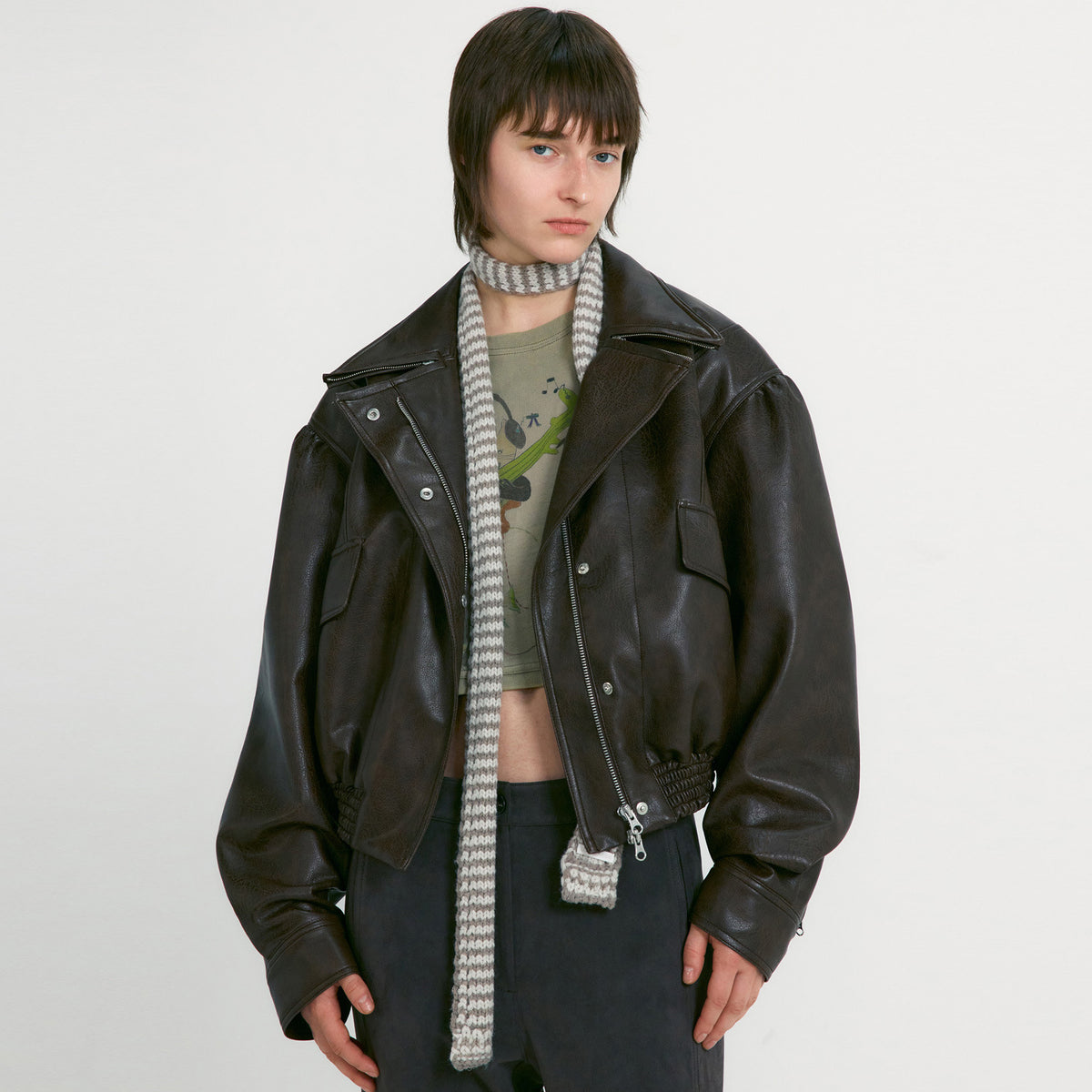 Women's black leather motorcycle jacket front view with snap buttons, zip pocket, knit scarf