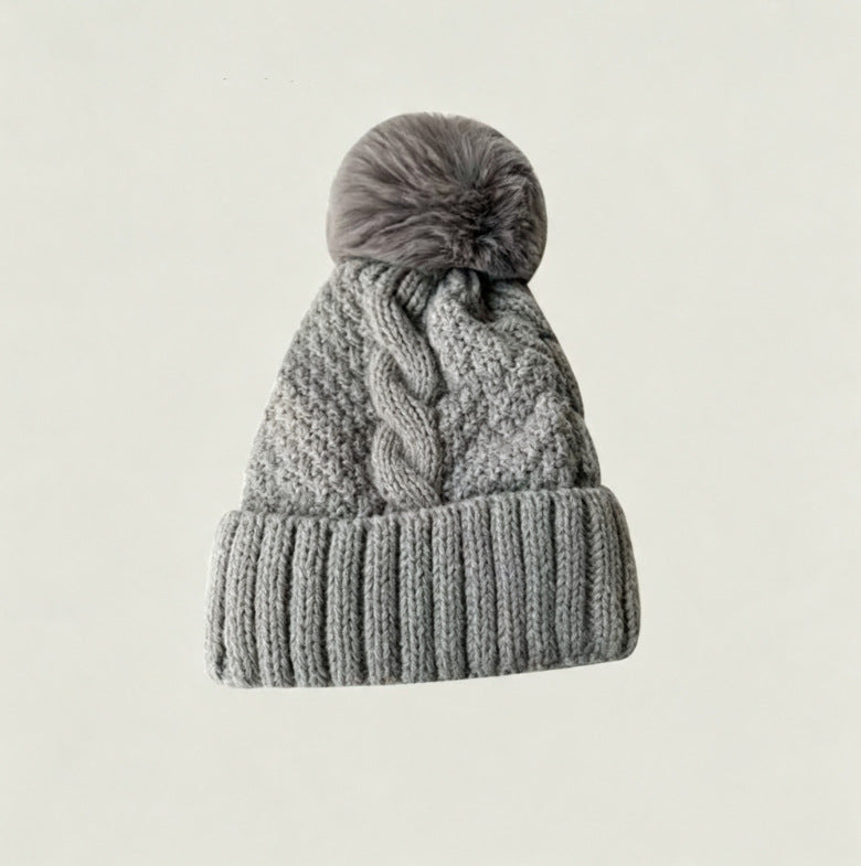 Gray cable-knit winter hat with ribbed cuff and fluffy pom-pom