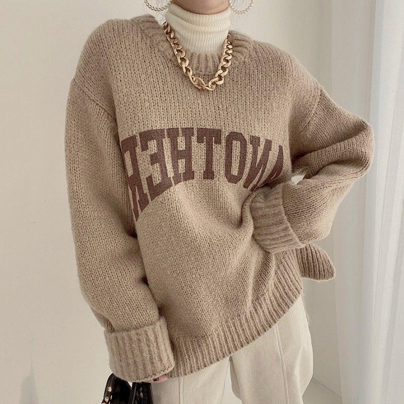 Tan chunky knit crewneck sweater with brown and black slogan band