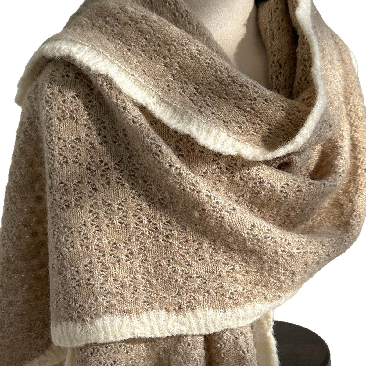 Taupe lace-knit wool scarf with openwork texture and fringed hem, folded.