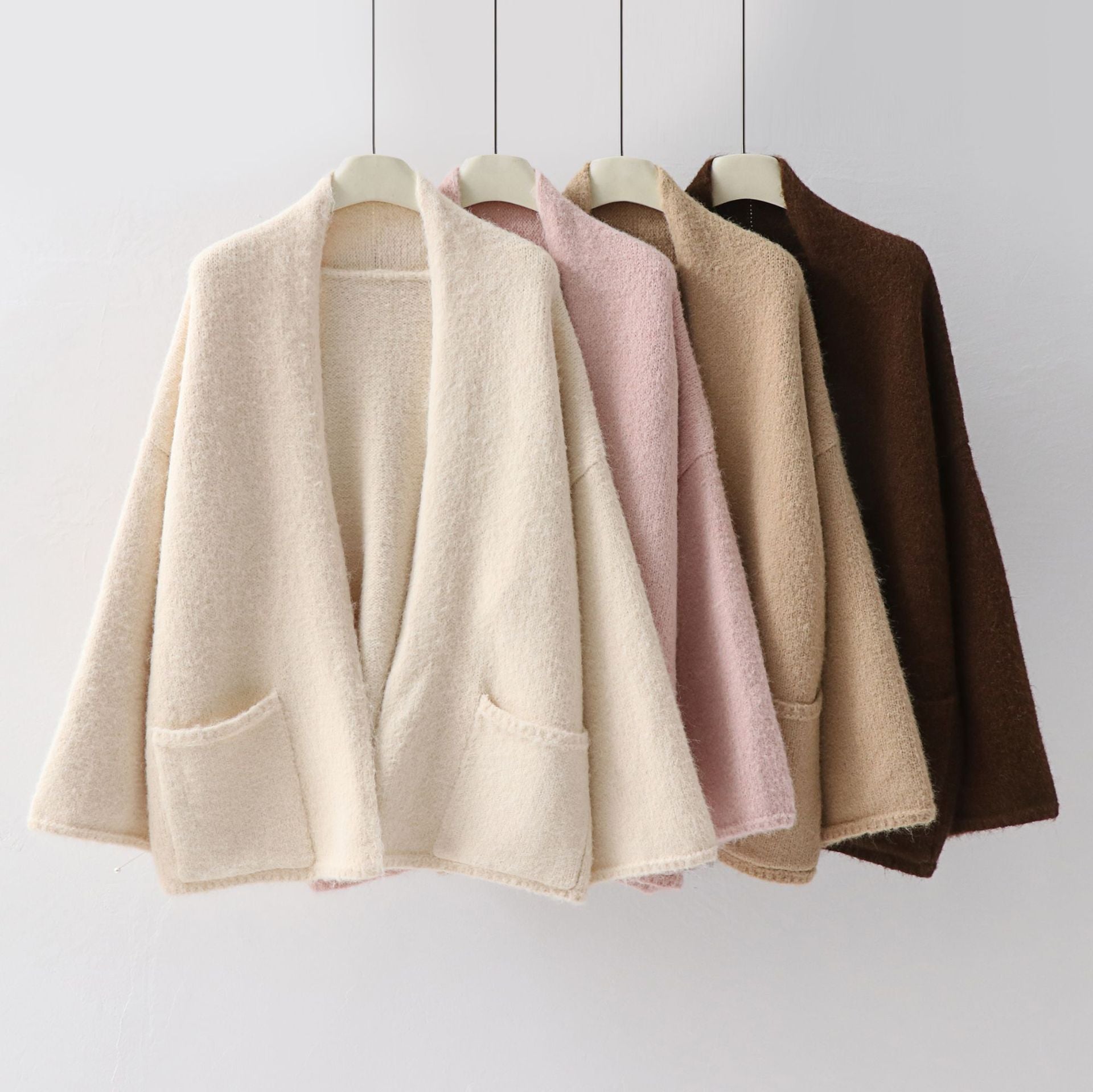 Wool cardigans on rack: loose shawl-collar knit with patch pockets, in beige, pink, brown