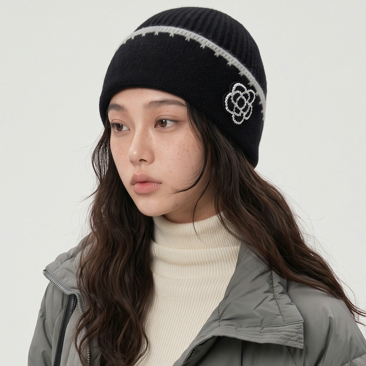 Black knit beanie with white trim and floral patch