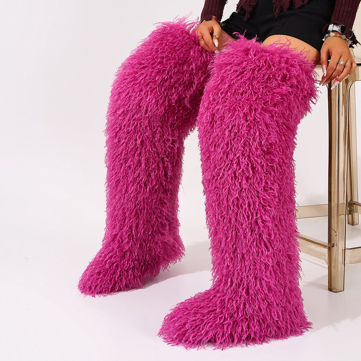 Bright pink faux-fur thigh-high boots with shaggy pile, shown worn on both legs.