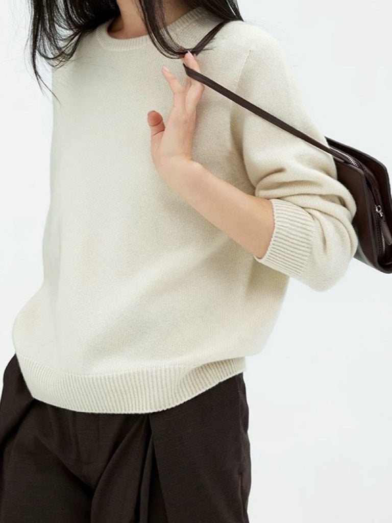 Off-white crewneck knit sweater with long sleeves, worn with dark pants