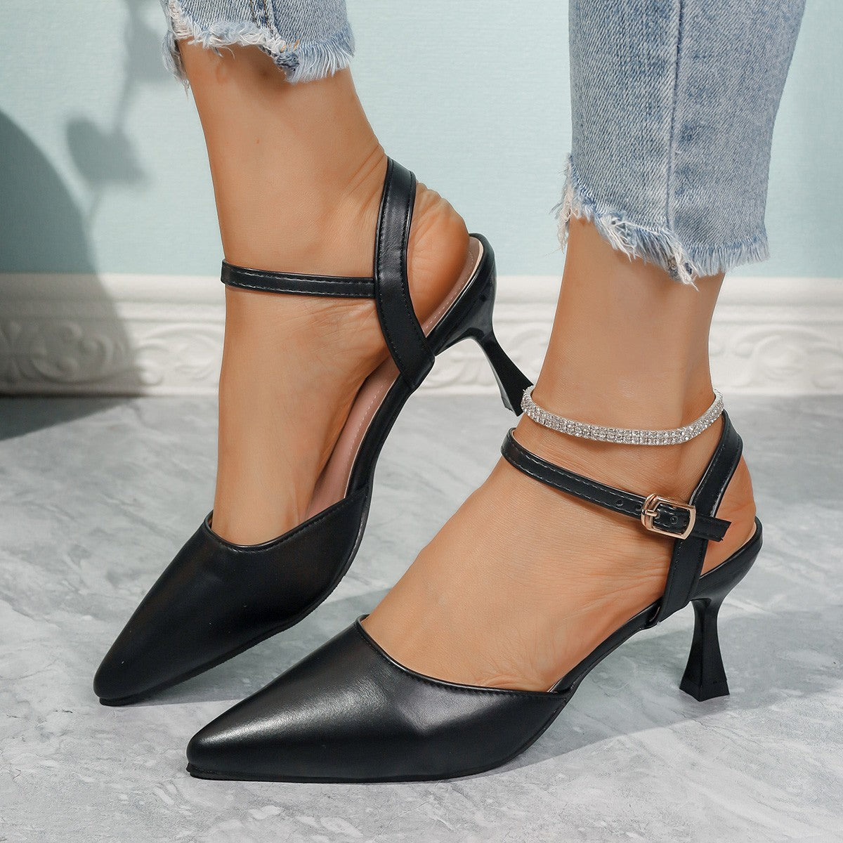 Black pointed-toe slingback heels with ankle straps and slim sculpted heels