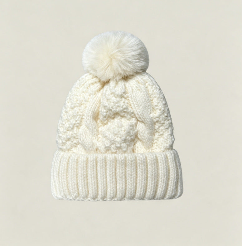 Off-white cable-knit winter hat with ribbed cuff and fluffy pom-pom