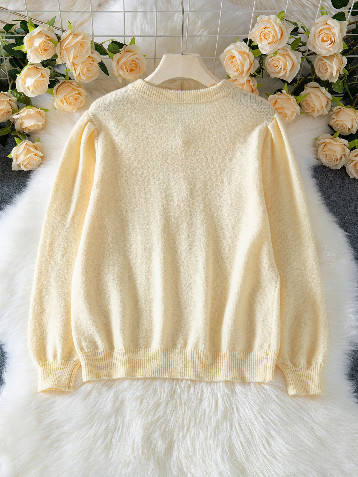 Back view of a cream knit cardigan with puff sleeves and a ribbed hem