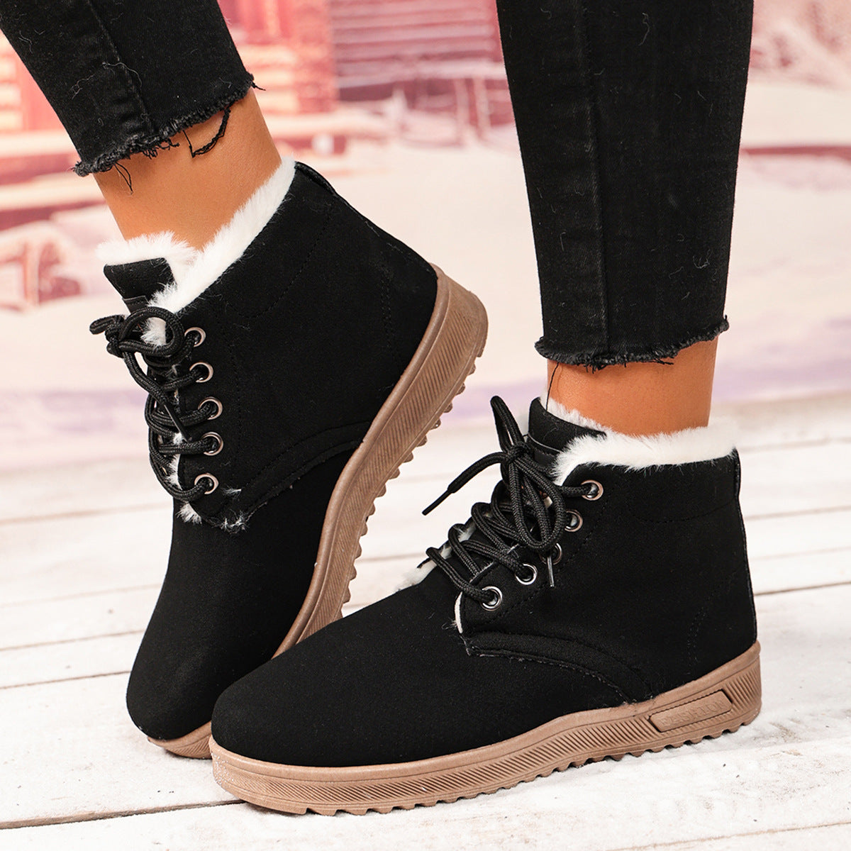 Black fleece-lined lace-up ankle boots with padded collars and brown soles, worn as a pair.
