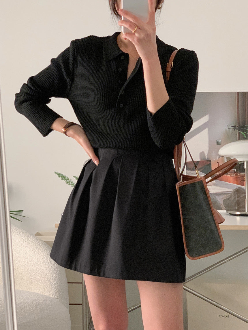 Black knit polo collar long-sleeve top with button placket and vertical ribbed texture.