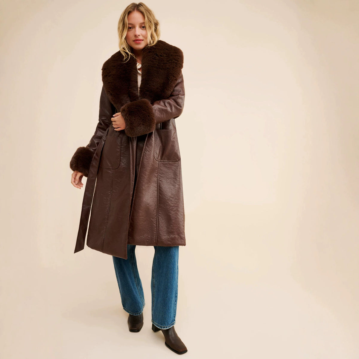 Brown long leather-look coat with faux fur collar, cuffs, and waist belt
