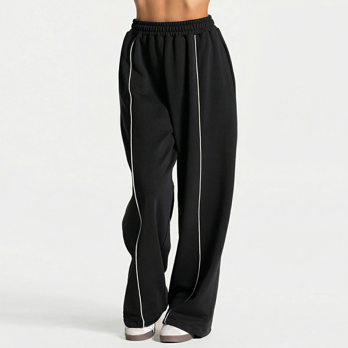 Loose yoga pants in black with elastic waistband and vertical white side stripe.