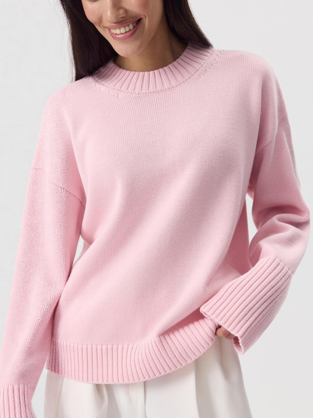 Women's pink knit sweater with crew neck and long sleeves, ribbed cuffs