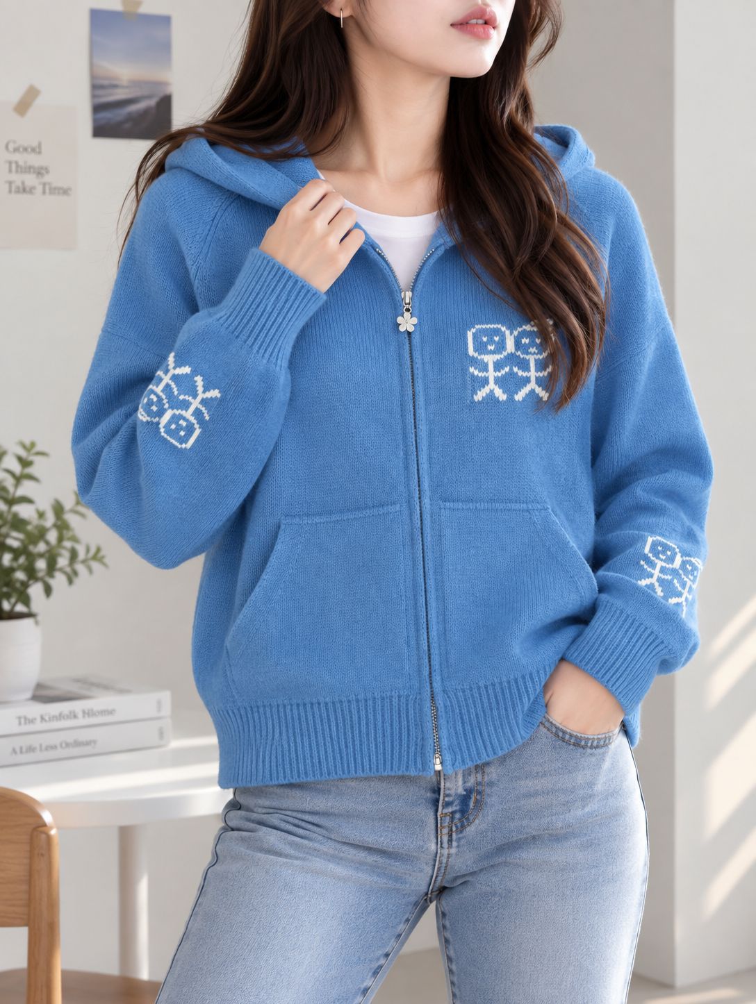 Blue zip-up hooded knit cardigan with graphic patches and front pockets.