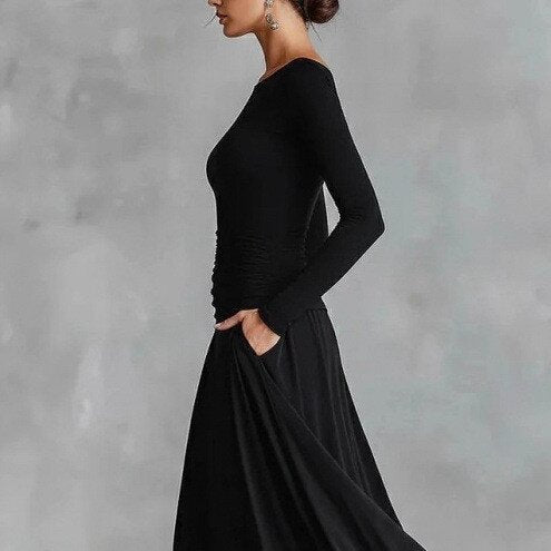 Black long-sleeve mermaid maxi dress with ruched waist and draped skirt detail, side angle