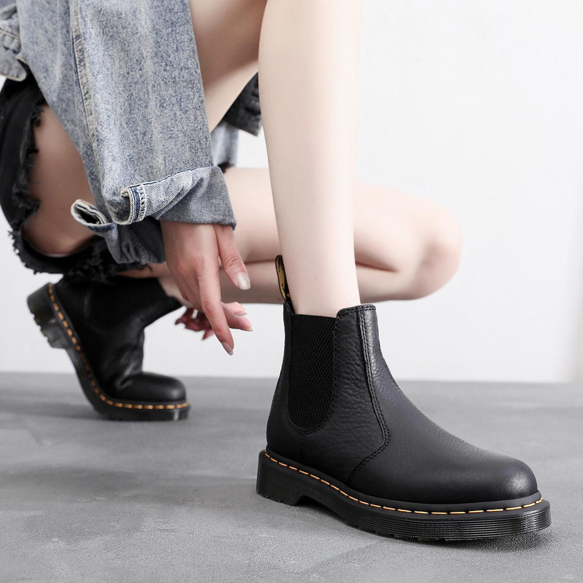 Black Chelsea boots with elastic gore and yellow stitch edging, low lug sole