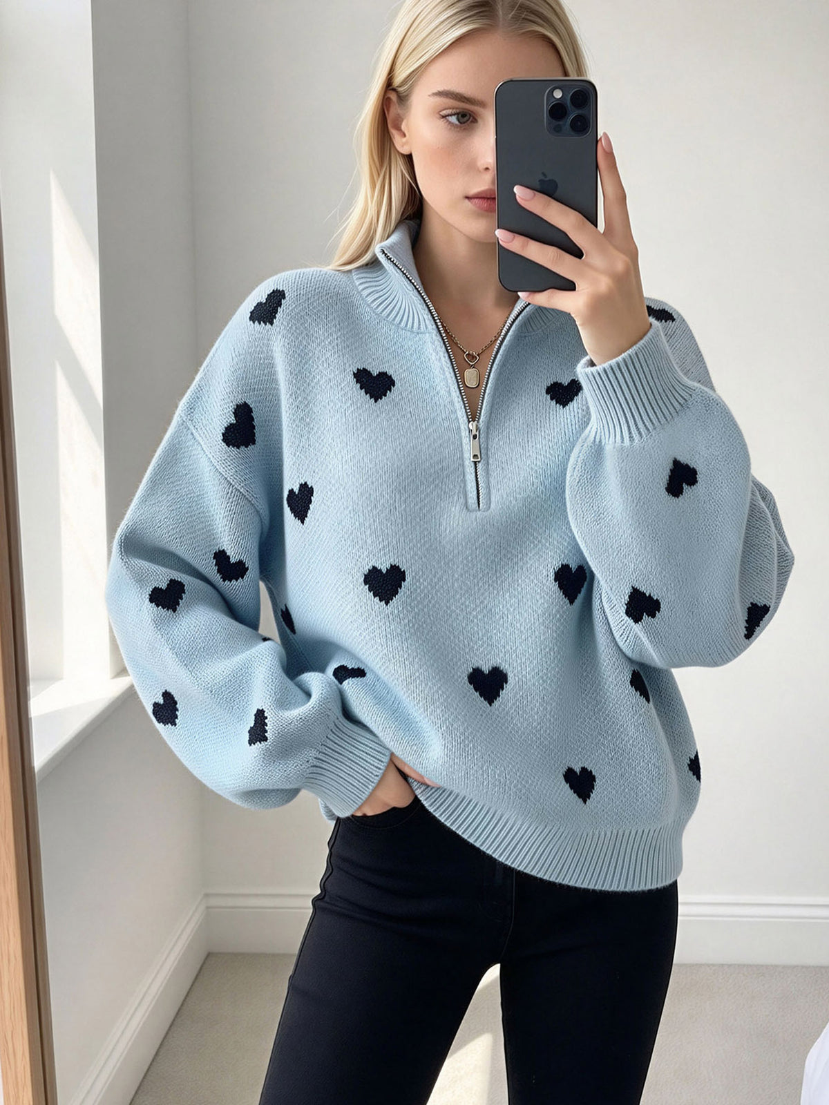 Light blue heart-pattern knit sweater with a quarter zip, high neck and ribbed cuffs.