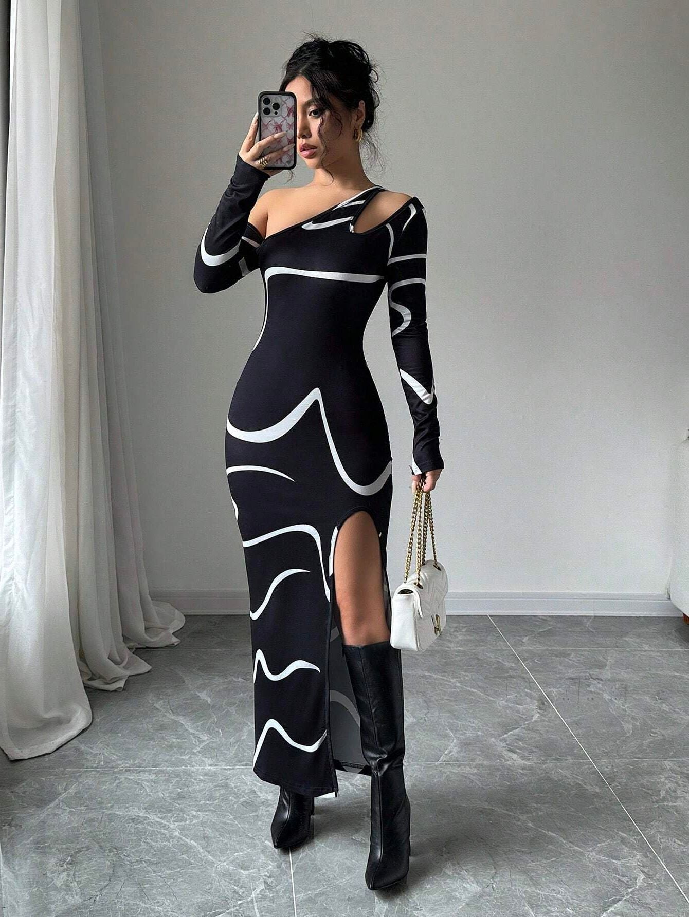 Black off-shoulder maxi dress with abstract wave print, long sleeves, high slit