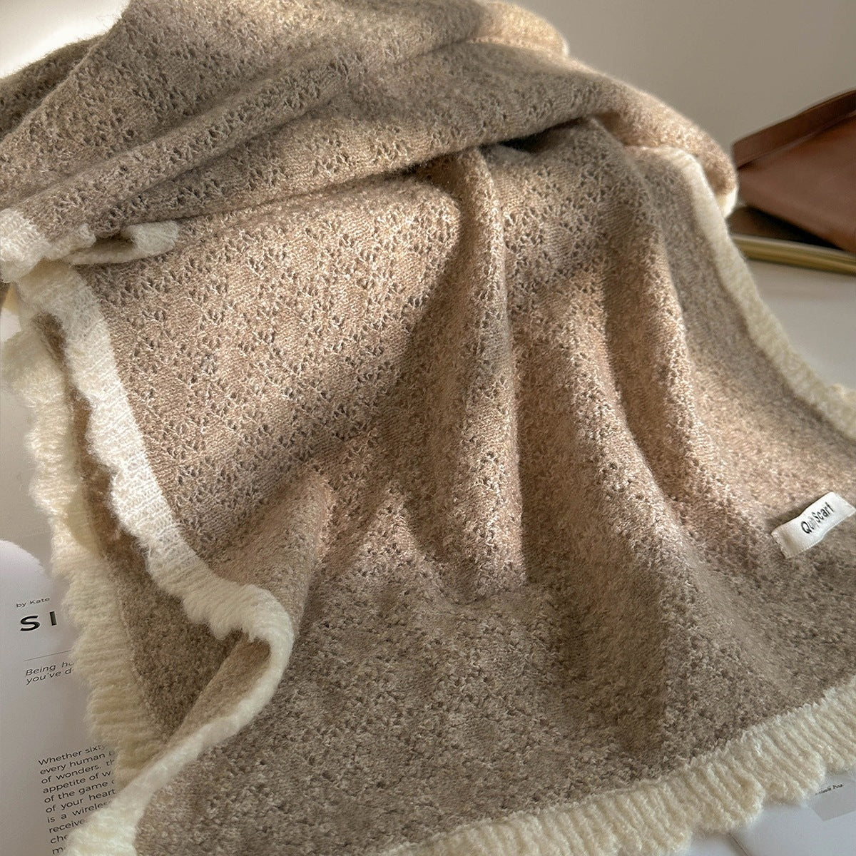 Beige lace-knit wool scarf with fringed trim and textured center panel, folded.