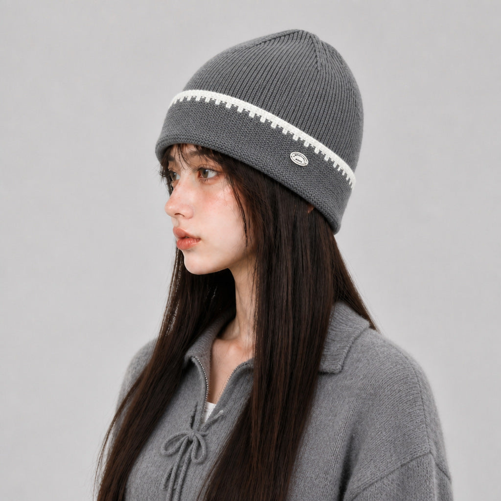 Gray knit beanie hat with white striped band and small oval logo patch