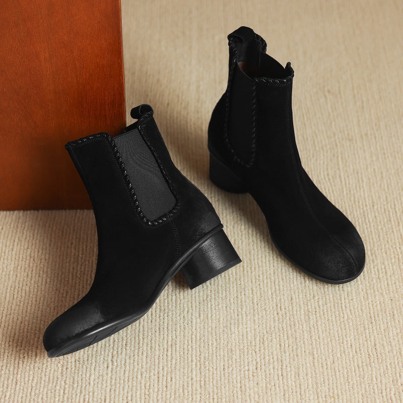 Black suede Chelsea ankle boots with round toe and chunky low heel, angled side view