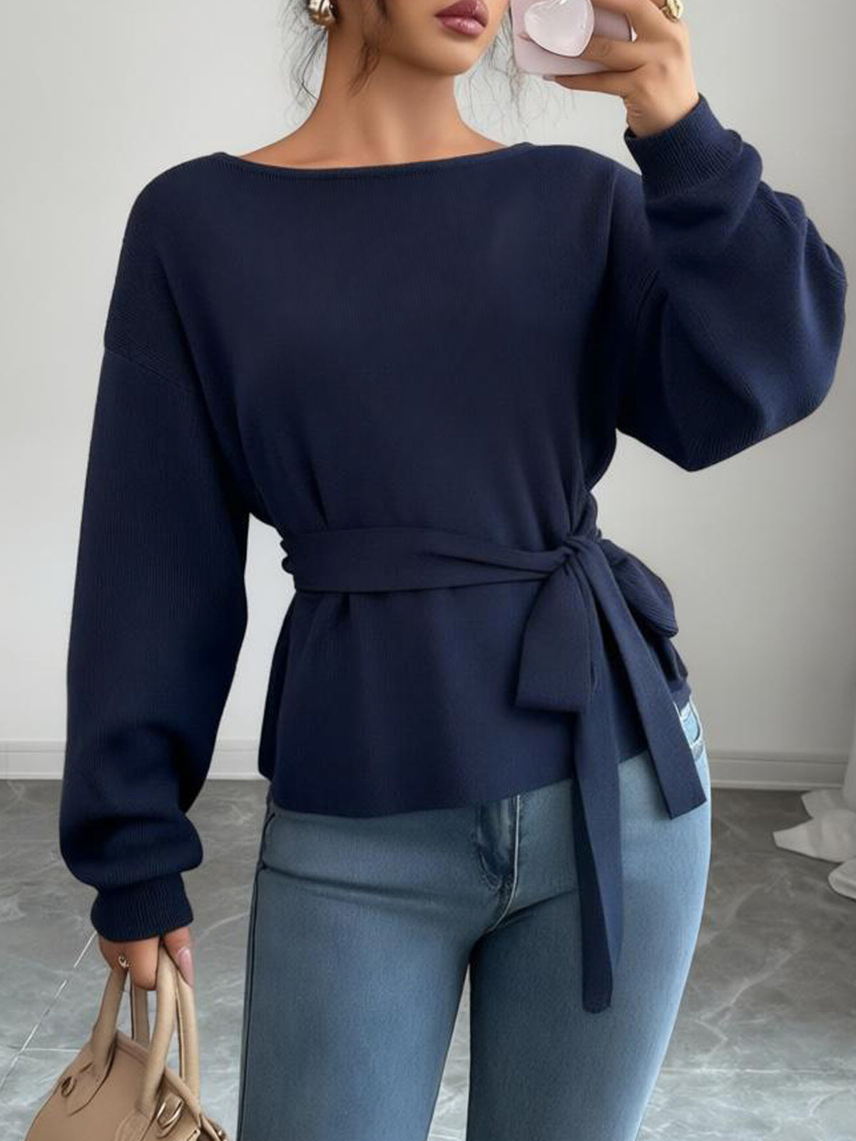 Front view of a women's dark blue sweater with a long waist tie