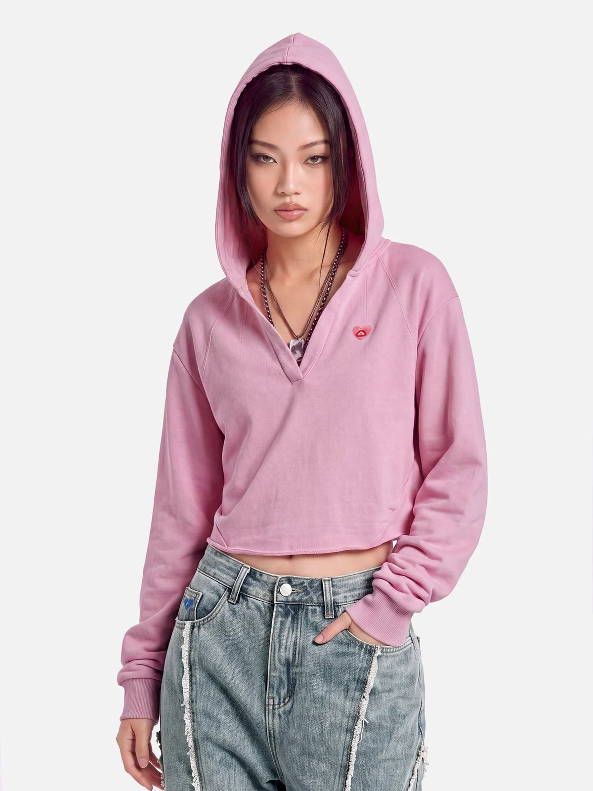 Pink cropped hooded sweatshirt with hood up, long sleeves, small chest logo